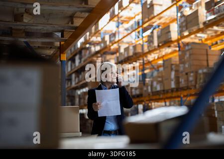Older warehouse manager making phone call. Stock Photo
