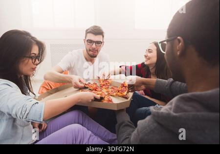 Students sharing pizza at home party Stock Photo