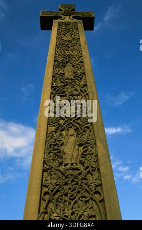 The Celtic cross in St Mary’s Churchyard, Whitby, is a striking 19th-century monument dedicated to Caedmon, the first known English poet. While not medieval itself, it was designed in 1898 to evoke the Anglo-Saxon heritage of Whitby Abbey. Carved from hard sandstone, the cross features intricate interlace patterns, biblical figures, and vine-scroll motifs characteristic of the Northumbrian style. It stands on the windswept cliffside, overlooking the North Sea, serving as a powerful visual link between the town’s Victorian literary revival and its ancient monastic roots. Stock Photo