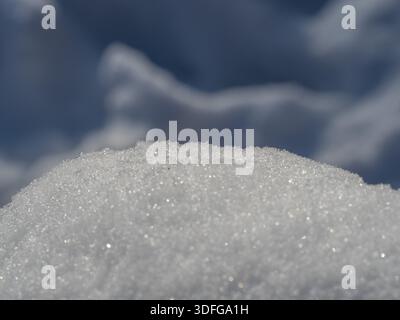 A close-up of a sparkling snow mound against a crisp blue sky, capturing the micro texture of ice crystals and the quiet, fresh mood of winter outdoor Stock Photo