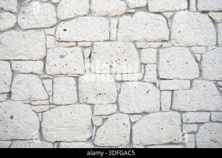 Alacati stone wall with natural limestone blocks forming irregular masonry texture as a rugged historical background Stock Photo