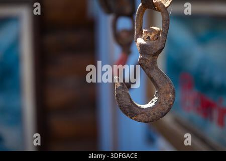 Rusty industrial lifting hook hanging from chain, showing corrosion, strength, and vintage industrial resilience Stock Photo