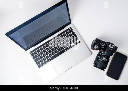 Top view flat lay with laptop, DSLR camera and smartphone on white background. Clean minimal mockup with copy space for technology, photography and re Stock Photo