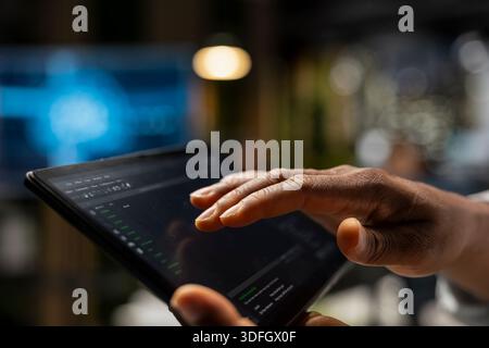 Close up of technician using tablet to write code, developing deep learning APIs. IT expert in tech startup using device to troubleshoot software errors, resolving system crashes Stock Photo