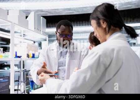 Team of lab experts working together, doing genetics study using clinical equipment. Teamworking colleagues using scientific gear in research facility, doing complex experiments Stock Photo