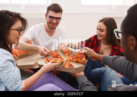 Students sharing pizza at home party Stock Photo