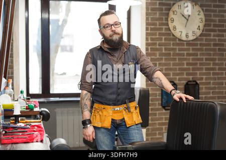 Bearded barber posing to camera at barbershop Stock Photo