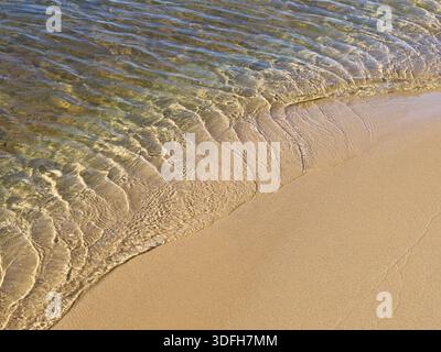 Wavelets form in receding lake waters on smooth sandy beach Stock Photo