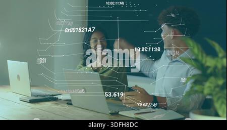 Fist-bumping colleagues wearing top and rolled-sleeves, working at office table with laptops and AR Stock Photo