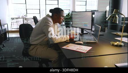Working mature man in white long-sleeve shirt typing on laptop at open-plan office, with charts Stock Photo