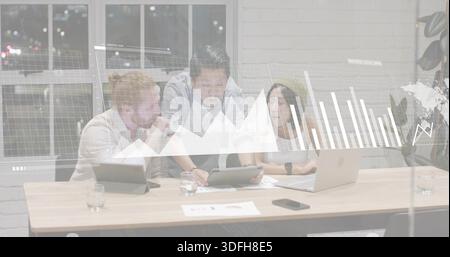 Analyzing data, three colleagues wearing business attire leaning in office, with tablet and laptop Stock Photo