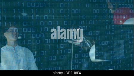 Recording woman with glasses, button-up and man in red top working in dark studio, binary code Stock Photo