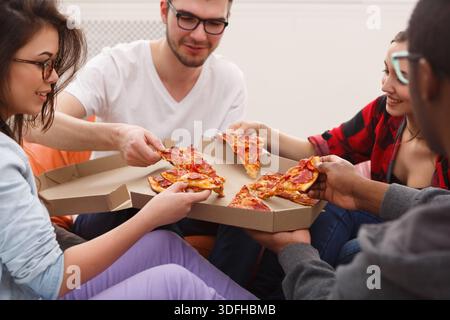 Students sharing pizza at home party Stock Photo