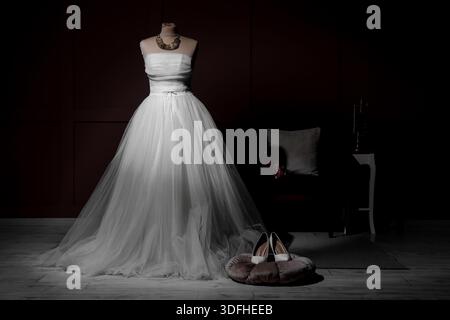 Mannequin with wedding dress and high heels in dark room Stock Photo