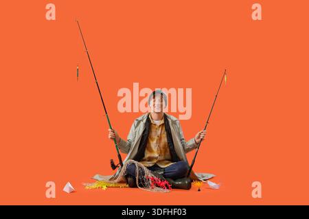 Funny young man with fishing rod on orange background Stock Photo