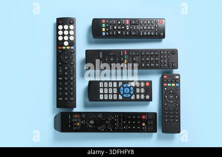 Different modern TV remote controls on blue background Stock Photo