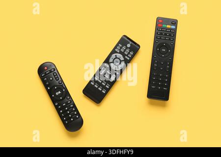Different modern TV remote controls on yellow background Stock Photo