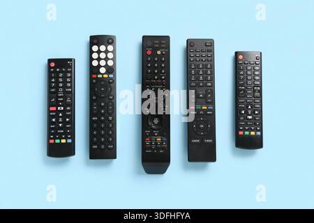 Different modern TV remote controls on blue background Stock Photo