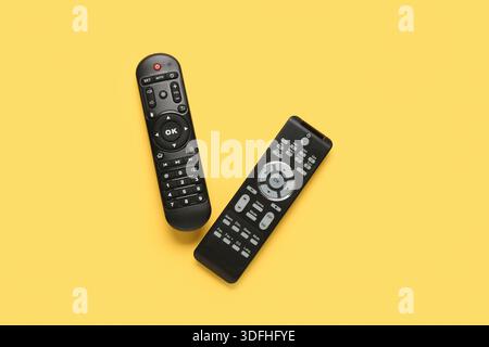 Different modern TV remote controls on yellow background Stock Photo
