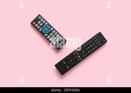 Different modern TV remote controls on pink background Stock Photo