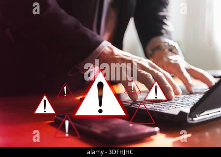Closeup of businessman typing on laptop with red warning icons and exclamation signs, representing cybersecurity threat, system error, data breach, ri Stock Photo