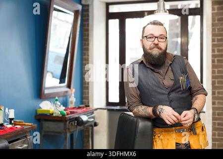 Bearded barber posing to camera at barbershop Stock Photo