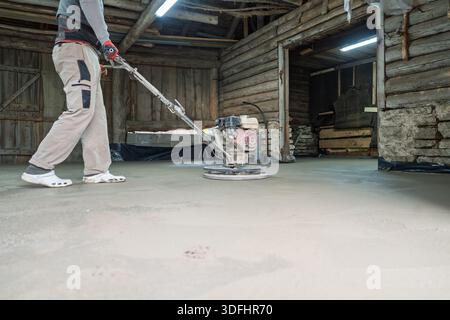 Concrete Polishing Worker Smoothing Surface with Grinding Machine in Rustic Building Stock Photo