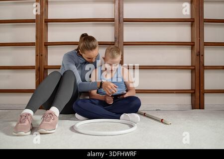 Woman Supporting Child with Down Syndrome Using Digital Tablet Together Stock Photo