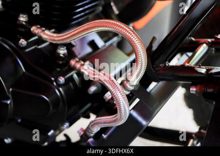 Close up shot detailed metallic braided oil cooler hose line connected strong black motorcycle engine block showing mechanical power sturdy complexity Stock Photo