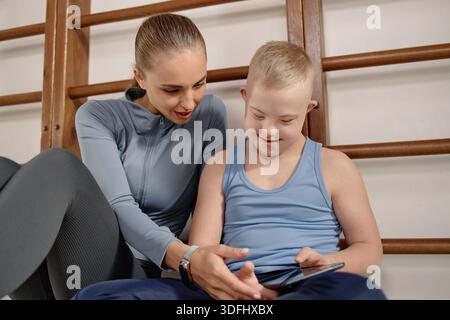 Woman Supporting Child with Down Syndrome Using Digital Tablet Stock Photo