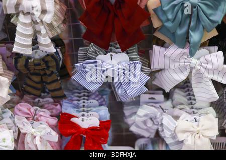 Collection of colorful hair bow accessory displayed on rack with varied ribbon pattern and satin texture showing playful cute style for kid fashion be Stock Photo