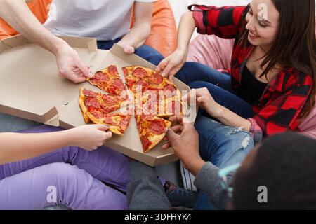 Students sharing pizza at home party Stock Photo