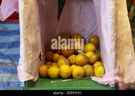 Fresh raw yellow passion fruit pile on green plastic basket in organic market stall with pink fabric background showing tropical agriculture harvest a Stock Photo