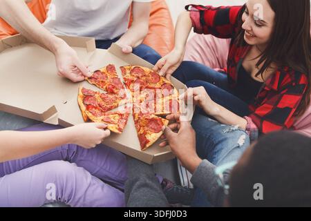 Students sharing pizza at home party Stock Photo