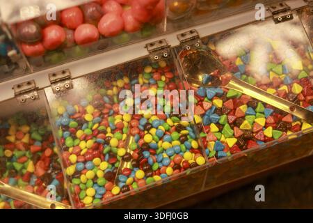 Colorful candy bin display featuring assortment of sweet chocolate treat and sugary snack inside clear container in dessert shop creating joyful child Stock Photo