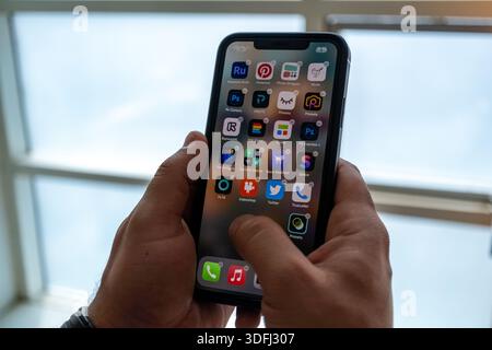 A person holding a smartphone displaying various app icons on the screen Stock Photo