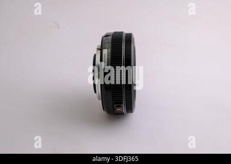 A close-up view of a black camera lens from the side, showcasing its textured grip and focus ring Stock Photo