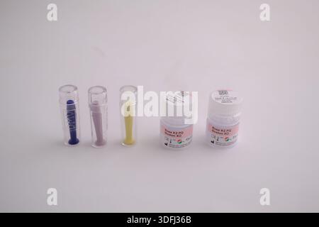 Various small containers and tubes of colored substances, arranged in a row on a white background Stock Photo