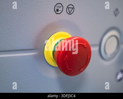 A close-up of a red and yellow emergency stop button on a machine panel Stock Photo