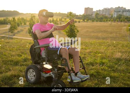Portrait of young disable man in wheelchair testing VR glasses in the park. Stock Photo