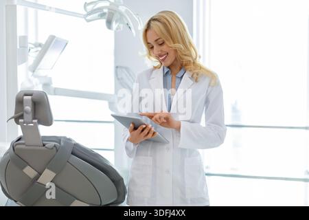 Blonde woman dentist using digital tablet at dental clinic Stock Photo