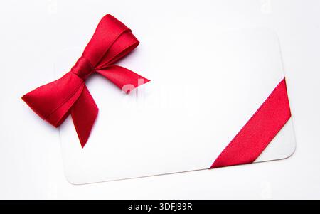 Blank white card featuring a red satin ribbon bow offering copy space Stock Photo