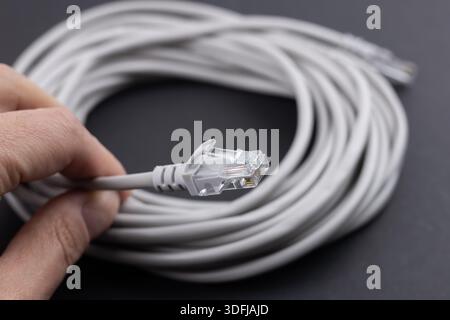RJ-45 crimped red ethernet connector, unshielded twisted pair UTP internet cable end in hand, macro, detail, closeup. Individual cables visible. Cable Stock Photo