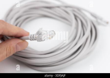 RJ-45 crimped red ethernet connector, unshielded twisted pair UTP internet cable end in hand, macro, detail, closeup. Individual cables visible. Cable Stock Photo