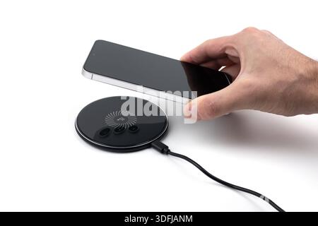 Man Charging Smartphone Using Wireless Charging Pad At Home. Stock Photo