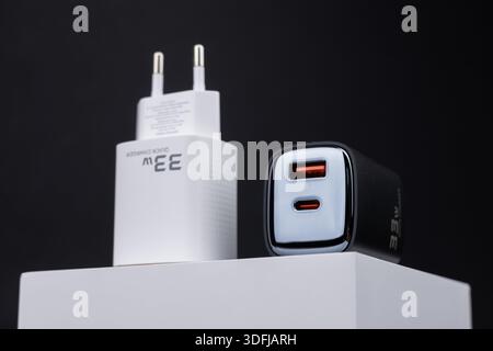 white and black smartphone chargers on dark background. Charger and USB cable type C on dark background. Stock Photo