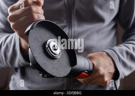 worker hold grinder tool on dark background. Stock Photo