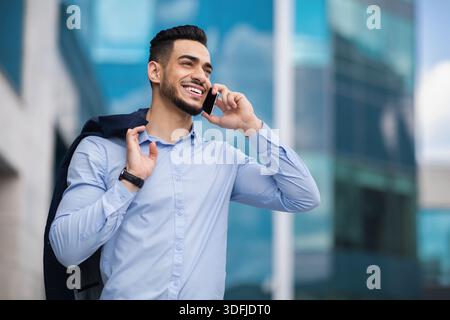 Happy muslim entrepreneur going home from job, talking on cellphone Stock Photo