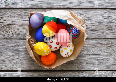 Colorful Painted Eggs Displayed in a Rustic Bowl on Wooden Surface During Festive Season Stock Photo