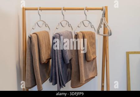 Brown and grey towels hanging on a wooden towel rack in a bright bathroom area. Spa theme home decor, fresh look, hygiene,bath accessories. Stock Photo